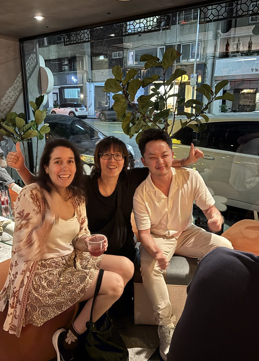 Three guests laughing together at a Taipei Weekend Social night, including a first-time visitor from abroad
